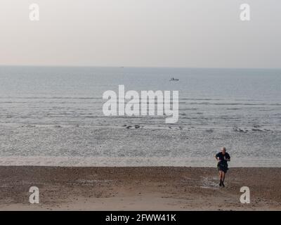 Rentner, die am Strand joggen, Großbritannien. Stockfoto