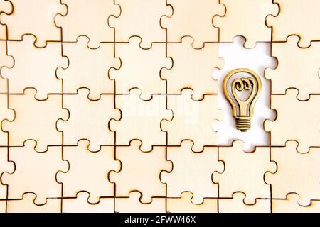 Holz Puzzle-Hintergrund mit zwei fehlenden Stücke und ein Kleine flache Stahlkopie einer Glühbirne Stockfoto