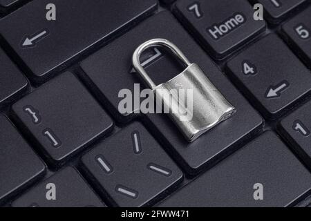 Nahaufnahme eines kleinen Vorhängeschlosses auf einer Laptop-Tastatur. Laptop-Sicherheit und Datenschutz-Konzept. Stockfoto