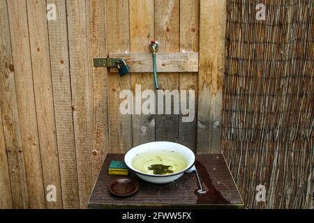 Der einfache Waschraum mit nur kaltem Wasser und Emaille-Becken. Sieht rustikal und schlecht aus Stockfoto