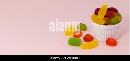 Marmelade und Süßigkeiten auf beigefarbenem Hintergrund mit Kopierfläche. Bunte Süßigkeiten in einer Schüssel. Stockfoto