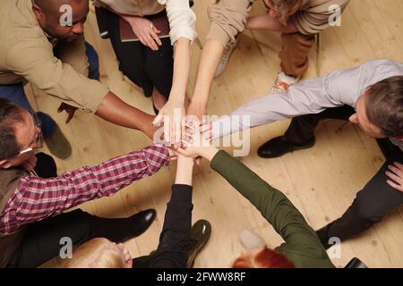 Große Gruppe interkultureller Menschen, die Stapel von Händen machen Holzfußboden Stockfoto
