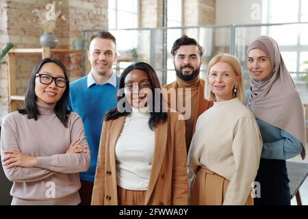 Gruppe von lächelnden jungen interracial Kollegen der modernen Firma stehen Gemeinsam im Loft Open Space Büro Stockfoto