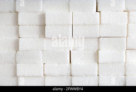 Weiße Zuckerwürfel Zusammensetzung aus Ziegelsteinwand, Zuckerhaufen, ungesunde Lebensmittel, Zutat, Süßigkeiten und Süßigkeiten Stockfoto