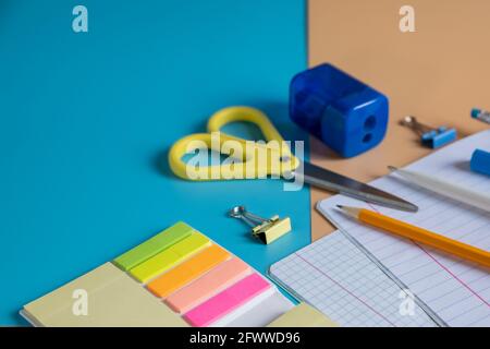 Schreibwaren. Farbenfrohe Gegenstände zum Studieren und Arbeiten im Büro auf blauem Hintergrund. Rückkehr zur Schule und zur Arbeit nach der Quarantäne. Stockfoto