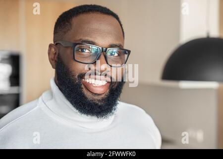 Freundlicher junger bärtiger afroamerikanischer Mann, der aus der Nähe der Kamera lächelt Gesichtsaufnahme Stockfoto