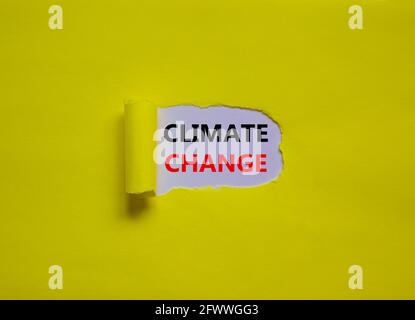 Symbol für den Klimawandel. Worte „Klimawandel“ erscheinen hinter zerrissenem gelbem Papier. Schöner gelber Hintergrund, Kopierbereich. Business, ökologisch und Kl Stockfoto