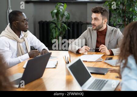 Zwei interkulturelle Geschäftsleute, die bei einem Treffen beraten oder Brainstorming durchführen Stockfoto