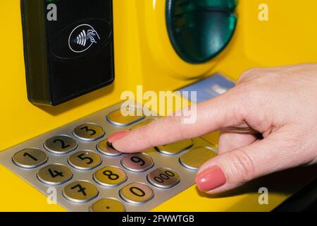 Eine Frau wählt den PIN-Code am Geldautomaten der Bank. Eine junge Frau gibt einen PIN-Code auf der ATM-Tastatur ein Stockfoto