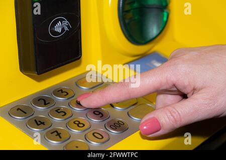 Eine Frau wählt den PIN-Code am Geldautomaten der Bank. Eine junge Frau gibt einen PIN-Code auf der ATM-Tastatur ein Stockfoto