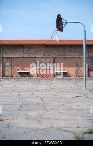 Ein veraltetautes Gebäude und ein verlassene alte Basketballplatz Stockfoto