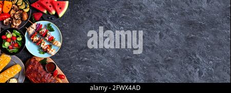 BBQ- oder Picknick-Food-Seite im Sommer grenzt an einen dunklen Steinbanner Hintergrund. Gegrilltes Fleisch, Gemüse, Obst und Salat. Draufsicht mit Kopierbereich. Stockfoto