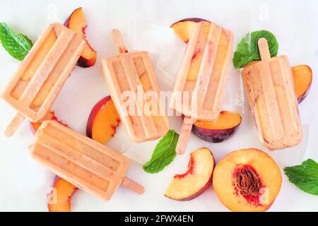 Sommer Pfirsich Joghurt Eis Pops, Draufsicht verstreut auf einem weißen Marmor Hintergrund Stockfoto