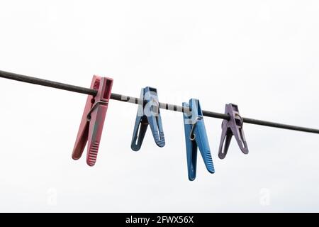 Plastikkleidernadeln an einem Seil. Eine Reihe mehrfarbiger Klamottenclips. Stockfoto
