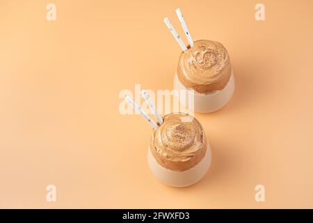 Zwei Gläser Kaffee-Dessert mit Schlagschaum auf orangefarbenem Hintergrund. Stockfoto