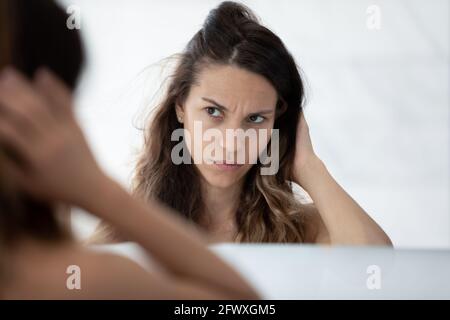 Ernst traurig Millennial Mädchen besorgt über trockene schlecht geschädigtes Haar Stockfoto