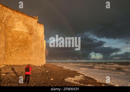 Birling Gap, Eastbourne, East Sussex, Großbritannien. Mai 2021. Regenbogen gegen stürmische Wolken, wenn die Sonne durchbricht und Orange auf Klippen leuchtet. Eine steife Südbrise peitscht die Brandung mit häufigen kiesigen Duschen. Kredit: David Burr/Alamy Live Nachrichten Stockfoto