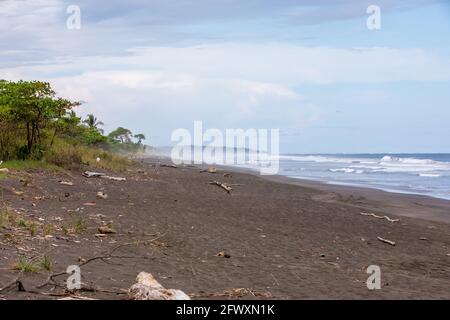 Blick auf den schwarzen, vulkanischen Strand und die Wellen des Pazifischen Ozeans an der Playa Hermosa im Norden von Puntarenas, Costa Rica Stockfoto