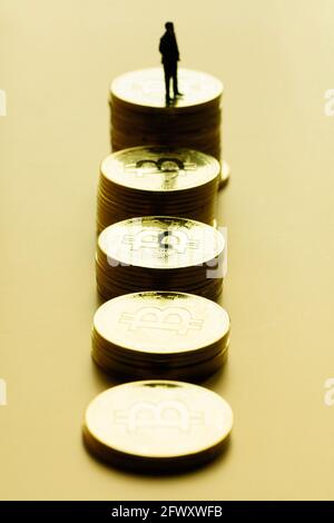 Bild von Stapel von Bitcoins vor einem goldenen Hintergrund mit Business-man-Miniatur auf der Münze. Vertikales Bild des aufwärtstrends des Bitcoin-Marktes. Stockfoto