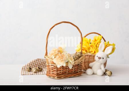 Schöne Osterkomposition mit Narzissen-Blumen, Wachteleiern und Spielzeug auf hellem Hintergrund Stockfoto