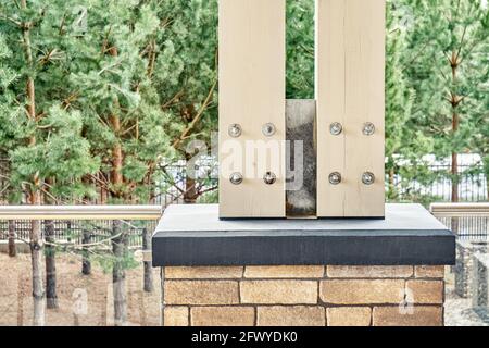 Unterstützung von Holzstangen für Dach über der Terrasse an überhängend Betonfundament mit Ziegel gegen junge Kiefern verziert Stockfoto