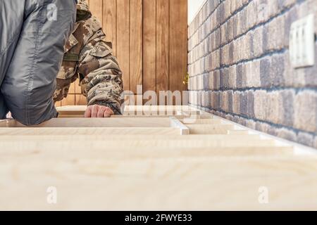 Zwei Arbeiter montiert Sperrholzrahmen für eine Küchenarbeitsplatte auf Küchenmöbel aus Sperrholz und massiver Holzasche in der Nähe Blick auf die Ziegelwand aus der Nähe Stockfoto