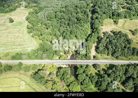 Luftaufnahme einer Autobahn mit Brücke durch die Grüner Sommerwald und Ackerland Stockfoto