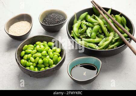 Rohe Sojabohnen mit Edamame und Salz und Sauce auf hellgrauem Hintergrund. Stockfoto