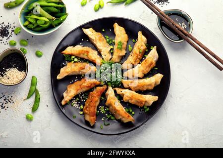 Gebratene Gyoza-Knödel mit Sojasauce und Zwiebel auf hellgrauem Hintergrund. Draufsicht Stockfoto