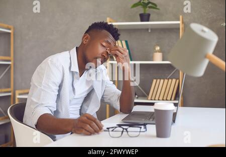 Müder Mann, der an einer Belastung der Augen des Computers leidet, reibt Nasenrücken Sitzen am Schreibtisch Stockfoto