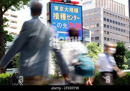 Tokio, Japan. Mai 2021. Menschen passieren ein Schild, um ein Regierungsgebäude zu führen, in dem am 24 Dienstag, dem 25. Mai 2021, in Tokio ein staatlich betriebenes Massenimpfzentrum für COVID-19 eröffnet wurde. Die von den japanischen Selbstverteidigungskräften betriebenen Massenimpfzentren wurden in Tokio und Osaka für Menschen ab 65 Jahren eröffnet. Quelle: Yoshio Tsunoda/AFLO/Alamy Live News Stockfoto