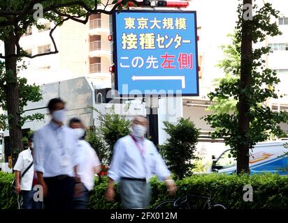 Tokio, Japan. Mai 2021. Menschen passieren ein Schild, um ein Regierungsgebäude zu führen, in dem am 24 Dienstag, dem 25. Mai 2021, in Tokio ein staatlich betriebenes Massenimpfzentrum für COVID-19 eröffnet wurde. Die von den japanischen Selbstverteidigungskräften betriebenen Massenimpfzentren wurden in Tokio und Osaka für Menschen ab 65 Jahren eröffnet. Quelle: Yoshio Tsunoda/AFLO/Alamy Live News Stockfoto