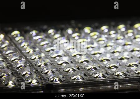 Nahaufnahme von stahlgrauen kleinen konvexen sphärischen Teilen auf der langen Platte der LED-Lampe oder des Panels. Konvexes Relief aus gemustertem Milchglas, selektiver Fokus. Pro Stockfoto