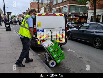 Ein Mann, der für den Waitrose Supermarkt online arbeitet, bestellt die Lieferung nach Hause und trägt Körbe mit Lebensmitteln auf einem Trolley, um eine Lieferung nach Hause zu machen. Stockfoto