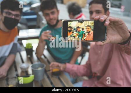 Drei Freunde trinken bei einem Ausflug nach der Blockierung des Coronavirus. Sie machen ein Gruppen-Selfie. Konzept der Freundschaft, neuer normaler, pandemischer Kampf. C Stockfoto