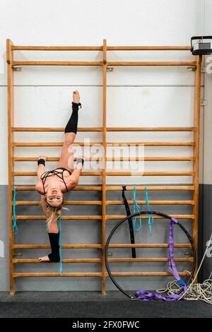Ganzkörper stark agil Weibchen in aktivem Ohr Durchführung Split-on Turnleiter im modernen Fitnesscenter Stockfoto