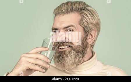 Glücklicher Bartmann, der Wasser trinkt. Lächelnder Mann mit transparentem Glas in der Hand Stockfoto