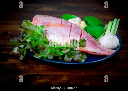 Nahaufnahme von frischem Fisch und Gemüse in keramischen Gerichten, die zum Kochen zubereitet werden. Stockfoto