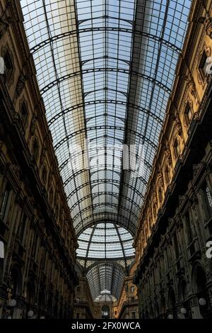 Perspektivischer Blick auf eine der beiden Arkaden, die mit einem Fassgewölbe aus Glas und Gusseisen versehen sind und unter einer verglasten Kuppel zu einem der elegantesten Einkaufszentren der Welt, der Gallerie Vittorio Emanuele II in Mailand, Lombardei, Italien, führen. Die Galleria, die von 1865 bis 1877 erbaut wurde, um die Piazza del Duomo und die Piazza della Scala, die das Opernhaus Teatro alla Scala beherbergt, zu verbinden, ist nach dem ersten Monarchen des Königreichs Italien benannt. Es beherbergt einige der bekanntesten High-End-Modemarken der Welt sowie Buch- und Kunsthändler und einige der ältesten und besten Restaurants der Stadt. Stockfoto