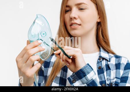 Junge Frau mit Sauerstoffmaske zur Behandlung von Atemproblemen, Coronavirus oder Covid-19 greifen die Lungen auf weißem Hintergrund an Stockfoto