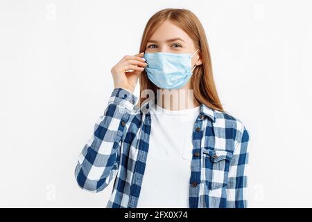 Junge Frau trägt eine schützende medizinische Maske auf dem Gesicht, auf isoliertem weißem Hintergrund, Gesundheits-, Sicherheits- und Pandemiekonzept Stockfoto