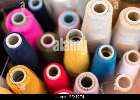 High-Angle-Hintergrundansicht von verschiedenen farbigen Kaschmirgarnen auf Konische Spulen in einer Strickfabrik mit Fokus auf ein Gelbe Haspel in der Mitte Stockfoto