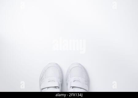 Flach lagen zwei weiße Sneakers teilweise unten In der Mitte mit freiem Platz für Text isoliert auf Ein weißer Hintergrund Stockfoto