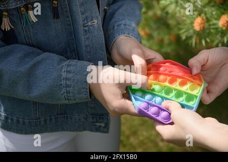 Mädchen spielen in beliebten Silikon Anti Stress Pop IT in Hexagon-Form Spielzeug. Nahaufnahme. Im Freien. Einfache Grübchen. Stockfoto