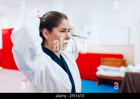 Junge Frau kleidet sich in ihrem Taekwondo-Anzug vor der Spiegel Stockfoto