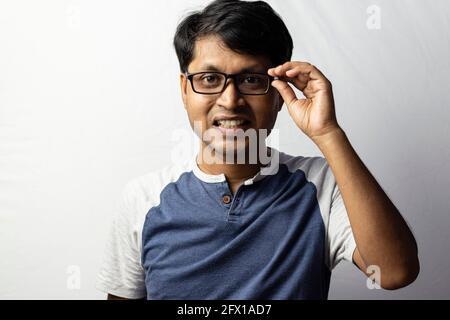 Ein indischer Mann mittleren Alters lächelte und hielt Brillen an Weißer Hintergrund Stockfoto