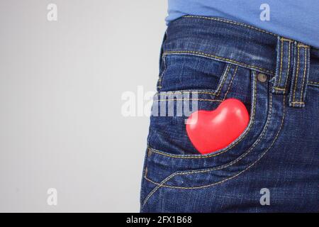 Rotes Herz in der Vordertasche der Hose. Denim-Tasche mit Herz-Nahaufnahme. Beziehung zwischen Menschen Stockfoto