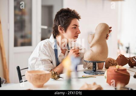 Frau, die ihre Töpferarbeiten auf Fehler überprüft Stockfoto