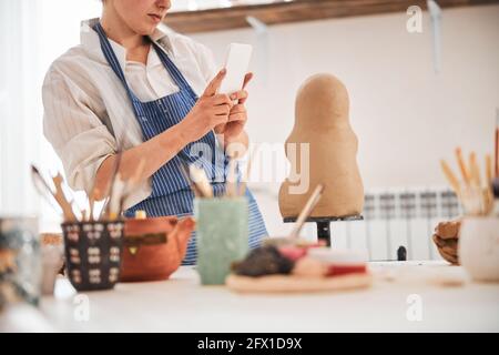 Person, die ein Foto auf ihrem Telefon mit einem Tonmodell fotografiert Stockfoto