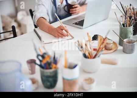 Person, die im Töpferladen Notizen auf dem Notizblock macht Stockfoto